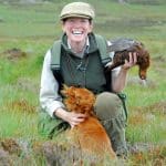 Woman with dog holds dead grouse during a shoot in Cumbria