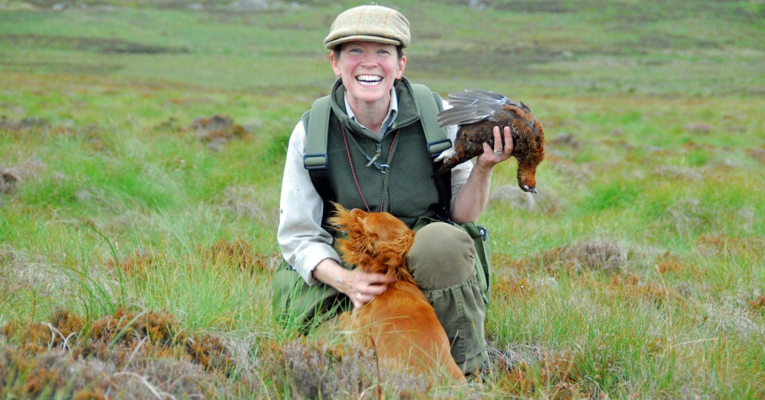 Woman with dog holds dead grouse during a shoot in Cumbria