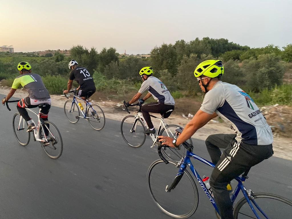 Gaza Sunbirds cycling on a road. IT is a sunny day and there is greenery by the side of the road. 