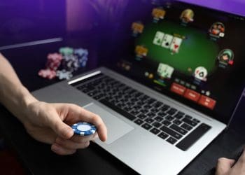 online casino man holding poker chip in front of laptop free