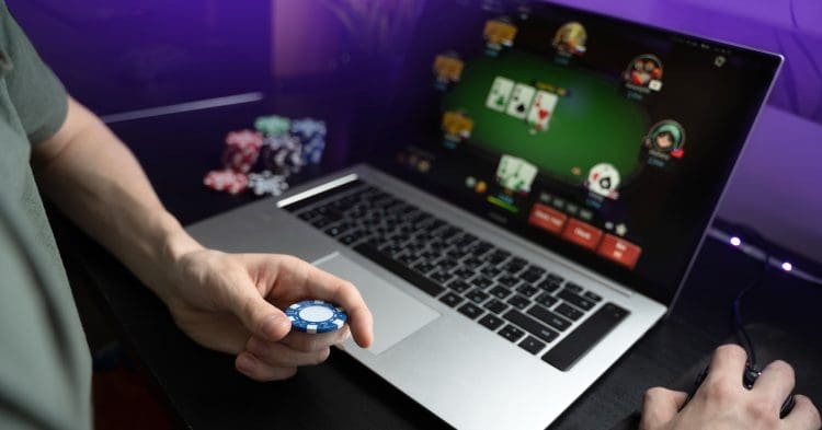 online casino man holding poker chip in front of laptop free