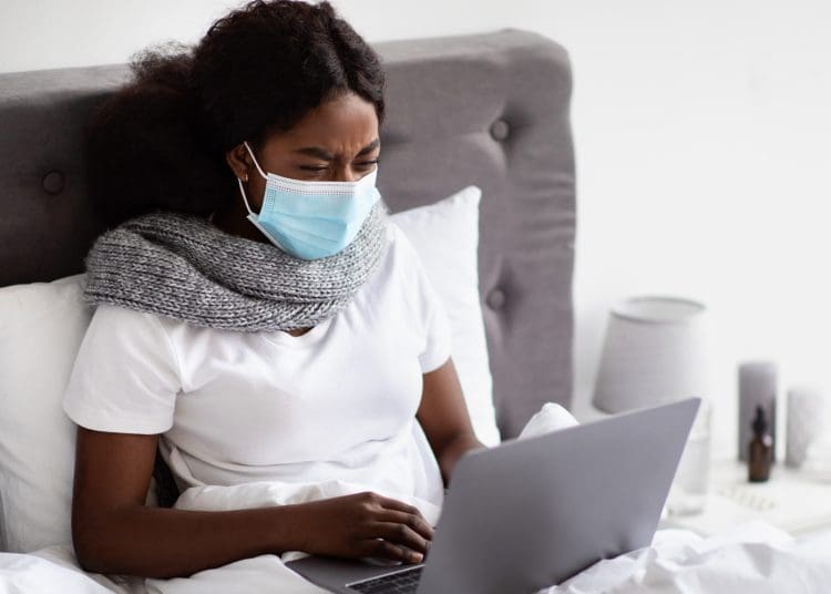 A woman wearing a mask in bed sick pay TUC