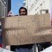 A greek call centre worker holding a placard that says you fucked with the wrong numbers