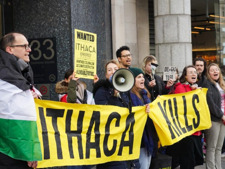 Fossil Free London activists protest outside Ithaca Energy's London office with Palestinian flags and a banner that reads: "Ithaca Kills".