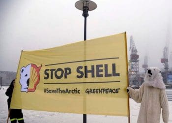 Greenpeace protesters with a stop Shell banner in the arctic one dressed as a polar bear net zero