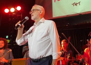 Jeremy Corbyn holding a mic in front of a band