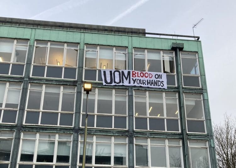 Manchester University a sign hanging from a window that reads UOM blood on your hands Israel