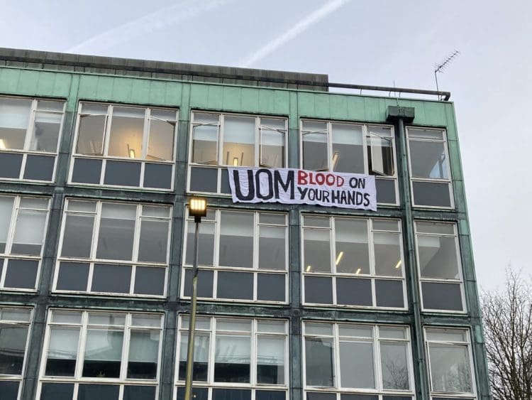 Manchester University a sign hanging from a window that reads UOM blood on your hands Israel