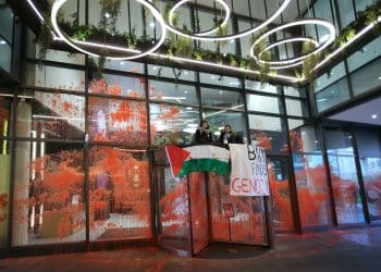 Palestine Action BNY Mellon action glass covered in red paint with two activists sitting