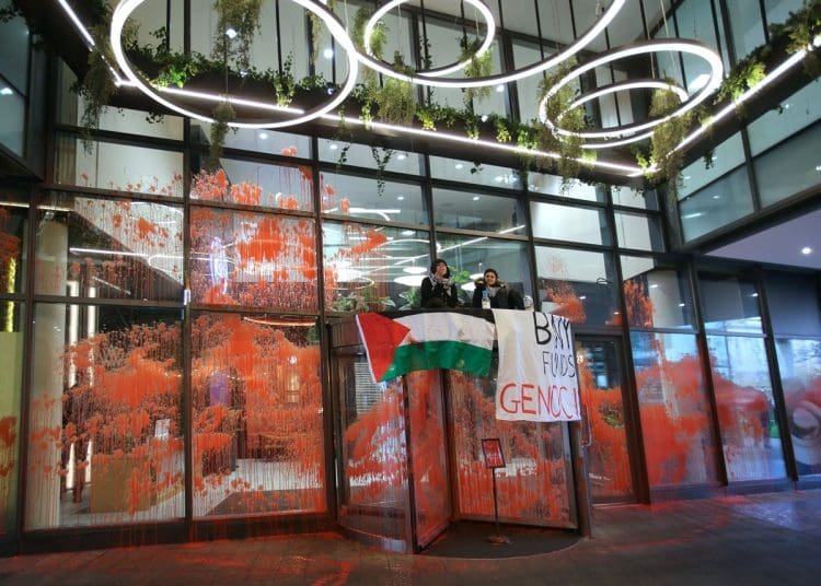 Palestine Action BNY Mellon action glass covered in red paint with two activists sitting