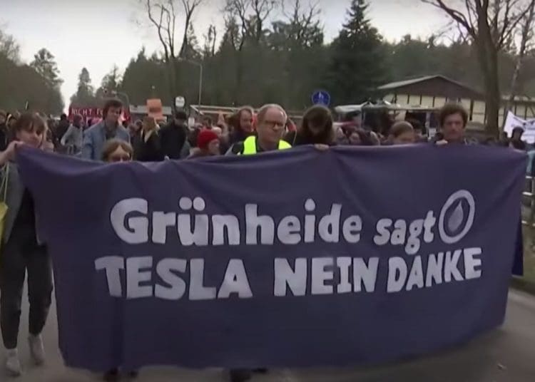 Protesters in Germany march with a banner that reads: "GrunHeide sagt TESLA NEIN DANKE" which translates to "Grunheide says TESLA NO THANKS" Musk