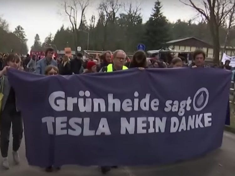 Protesters in Germany march with a banner that reads: "GrunHeide sagt TESLA NEIN DANKE" which translates to "Grunheide says TESLA NO THANKS" Musk