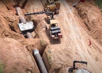 Construction workers lay an oil pipeline EACOP