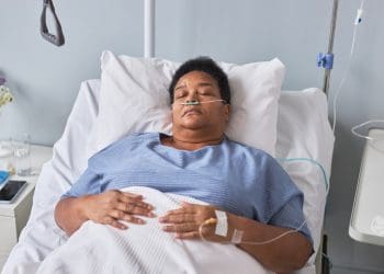 A woman with chronic illness lying in a hospital bed with ng feeding and an iv line