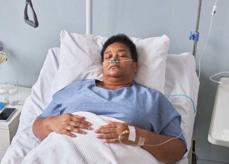 A woman with chronic illness lying in a hospital bed with ng feeding and an iv line