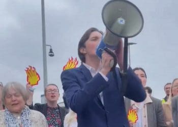 Protesters with a megaphone and Shell burning logos singing outside the company's AGM Shell AGM climate