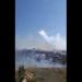 Israel bombing Lebanon with white phosphorus. White smoke and flames rise from an area of grassy hills and trees, with a few houses interspersed between World Environment Day ecocide
