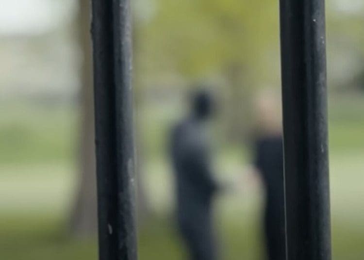 Prison bars, with someone in the distance blurred out behind Labour prison reform