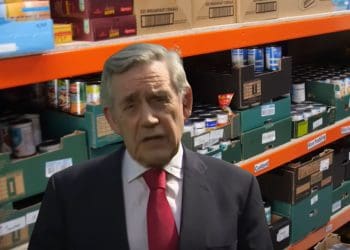 Former Labour leader Gordon Brown with foodbank shelves behind him Guardian