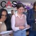 Three students opening A-level results with the UCAS logo universities