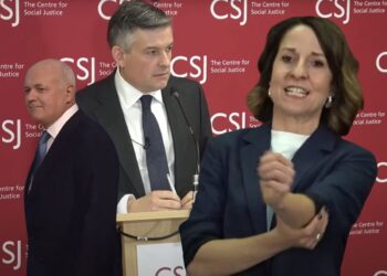 Jonathan Ashworth delivering a keynote at a CSJ event. Iain Duncan-Smith walking off to the left. Liz Kendall rolling up her sleeve with gritted teeth DWP CSL Labour