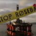 Yellow STOP ROSEBANK banner across a oil rig in the North Sea, with a red rose on top of the banner.