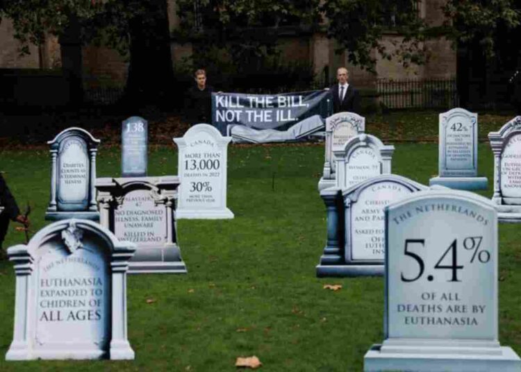 assisted dying a mock graveyard with tombstones carved with figures against assisted dying