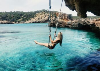 woman on a hammock above the crystal clear waters of a beach in Ibiza