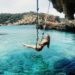 woman on a hammock above the crystal clear waters of a beach in Ibiza