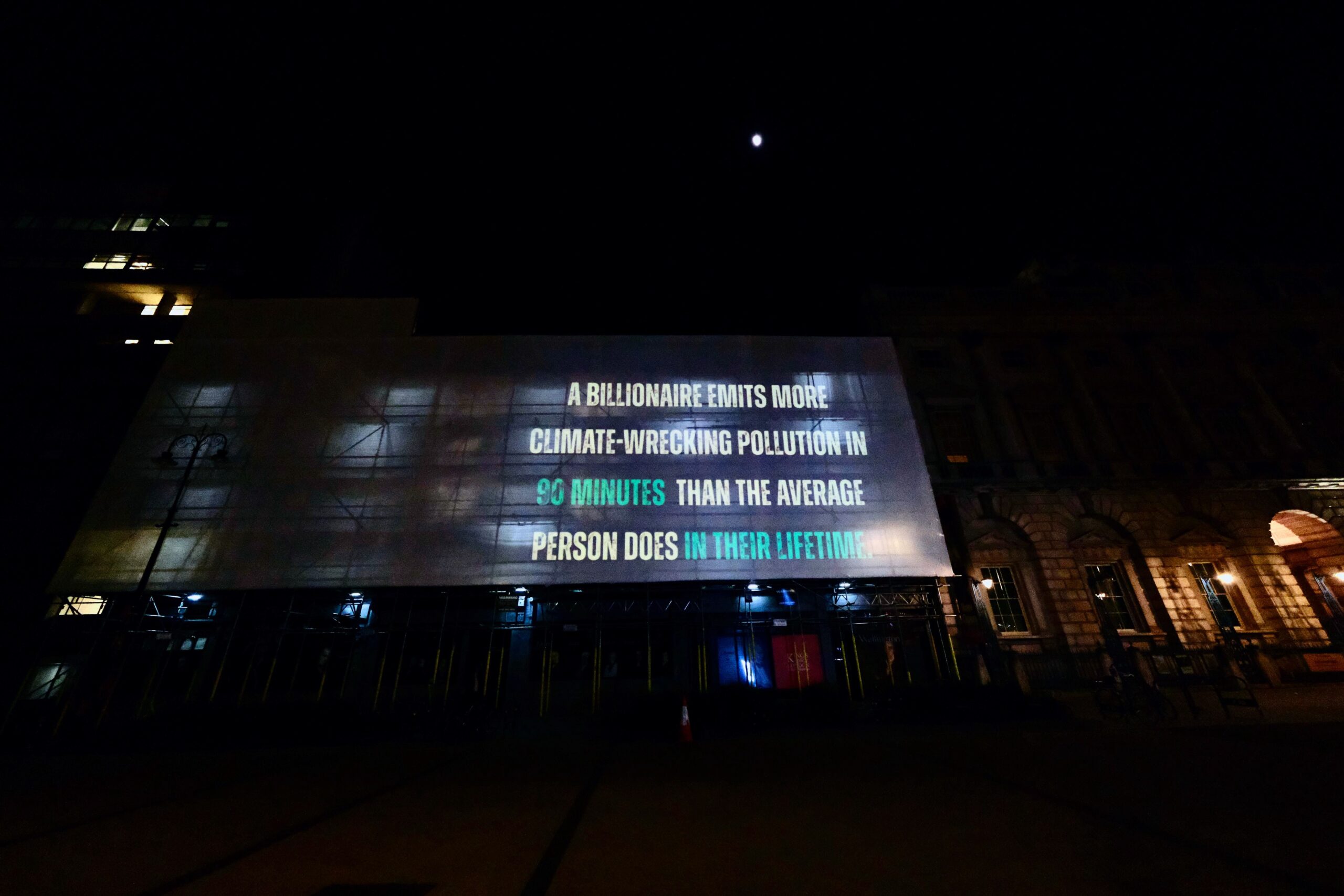 Projection at the Strand which reads: "A billionaire emits more climate-wrecking pollution in 90 minutes than the average person does in their lifetime."