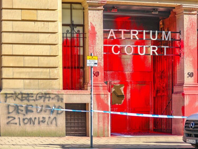 Spray-painted message on the entrance to Atrium Court reads "Free Gaza: defund Zionism". Red paint all over the front entrance, with police cordon stretching out in front.
