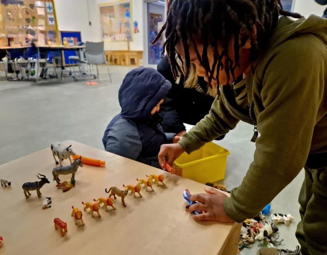 Children play with animal figurines. 