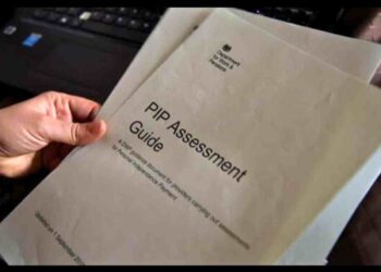 DWP: Someone holds a printed copy of a PIP assessment guide in their fingertips