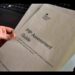 DWP: Someone holds a printed copy of a PIP assessment guide in their fingertips