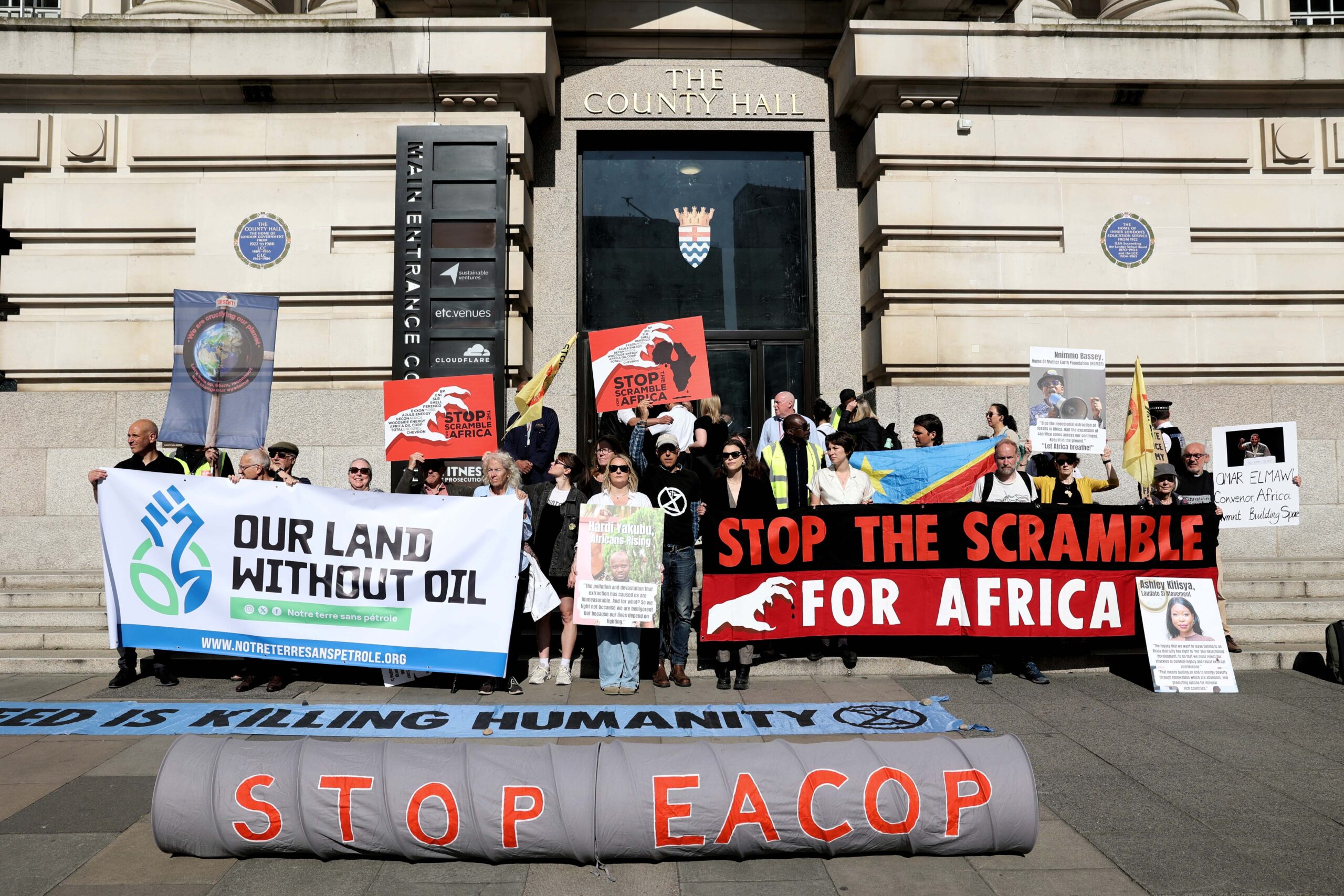 Activists gather outside Africa Energy Summit with banners reading: "Stop the scramble for Africa", "Stop EACOP" and "Our Land Without Oil". 