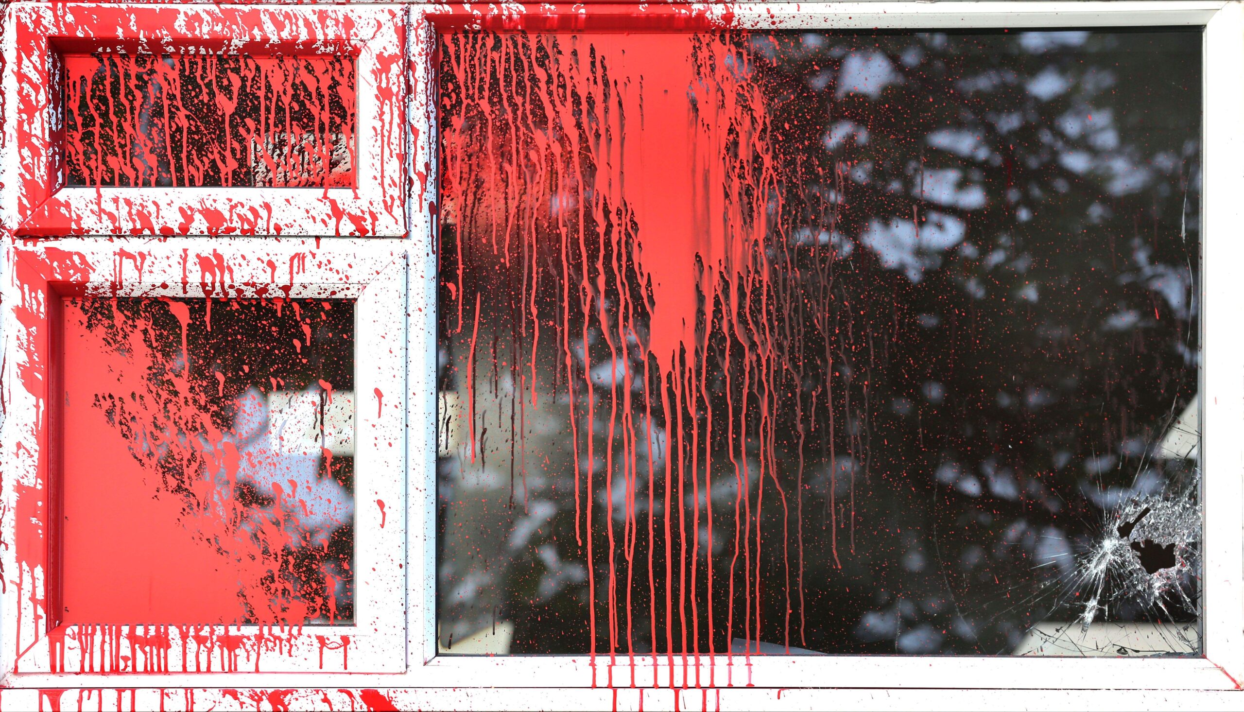 Red paint dripping down a window. 
