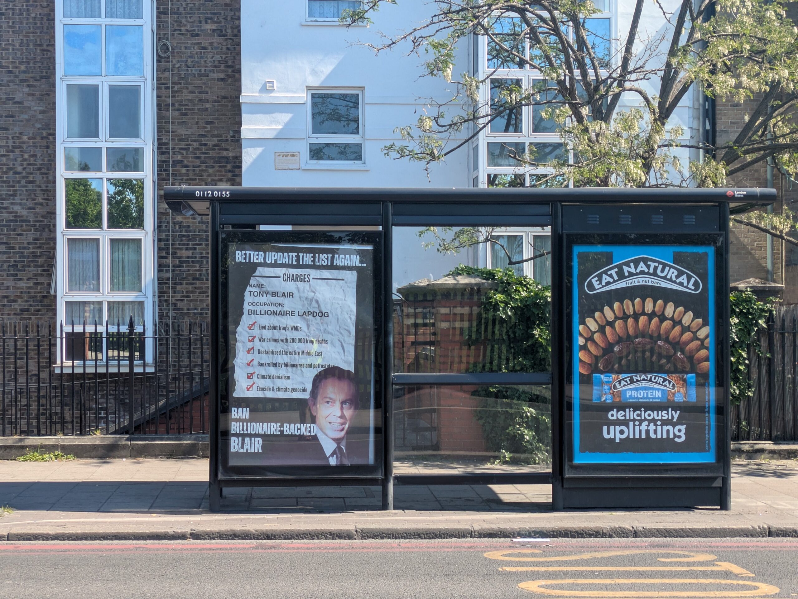 Tony Blair Institute brandalism on a bus stop which reads: BETTER UPDATE THE LIST AGAIN .. CHARGES NAME: TONY BLAIR OCCUPATION: BILLIONAIRE LAPDOG Lied about Iraq's WMDs War crimes with 200,000 Iraqi deaths Destabilised the entire Middle East Bankrolled by billionaires and petrostates Climate denialism Ecocide & climate genocide BAN BILLIONAIRE-BACKED BLAIR