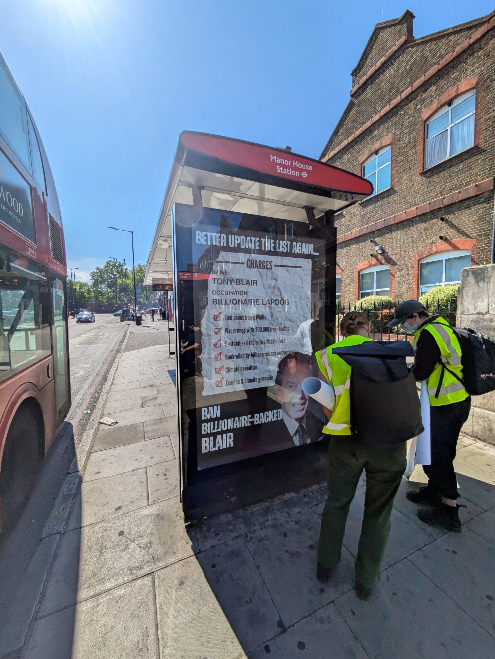 Advert on Manor House bus station stop, with activists in high vis viewing after installing it. 