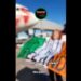 Activist holding Irish flag reading "US miliarty out of neutral Ireland" in front of a plane with red paint sprayed across the cockpit Palestine Action