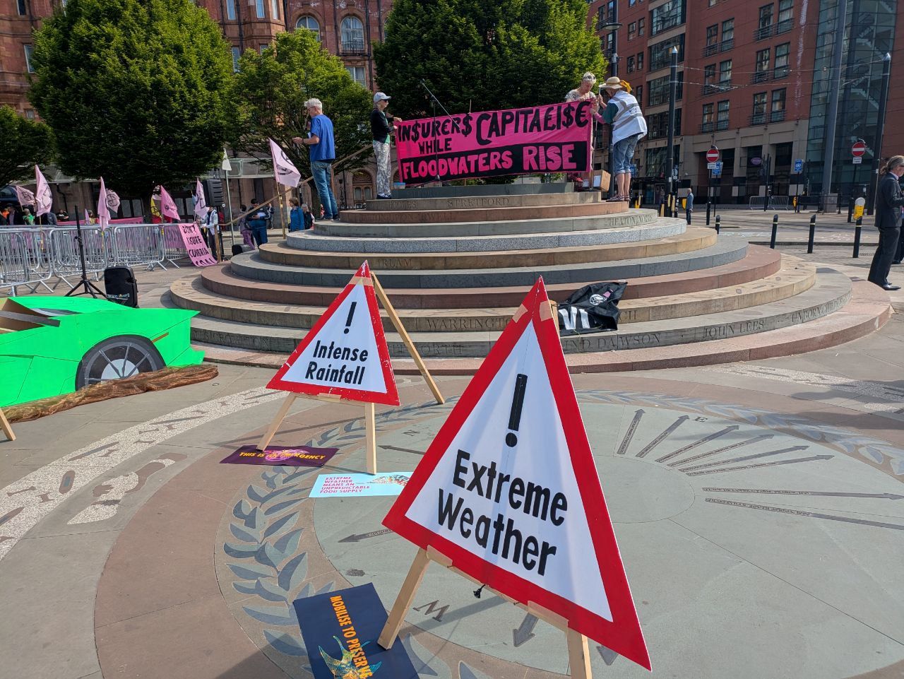 Extreme weather and intense rainfall hazard signs. A banner in the background reads: "Insurers capitalise, while floodwaters rise"