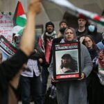 Protesters outside a Filton 18 court trial with Palestine flags and placards reading "Free Palestine Action Political Prisoners" with pictures of Filton 18 activists such as Jordan Devlin.