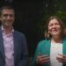 Left: Adrian Ramsay smiling in a suit and pink shirt. Right: Ellie Chowns speaking in a green blazer and cream blouse. Backdrop of greenery. Green Party leadership election