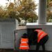 Two activists in high-vis vests leaning into an electrical services cabinet to cut cables JP Morgan