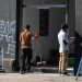 Two workers clean the entrance to Eagle Strategic Consulting where activists shattered windows and graffitied overnight DISMANTLE