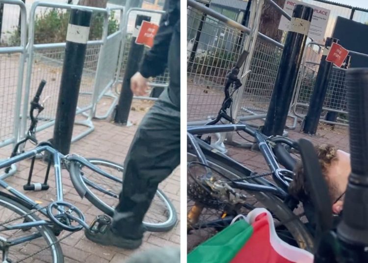 Activists use bike locks to lock-on with their bicycles to metal barricades outside Elbit Systems HQ. A Palestine flag is in view alongside them.