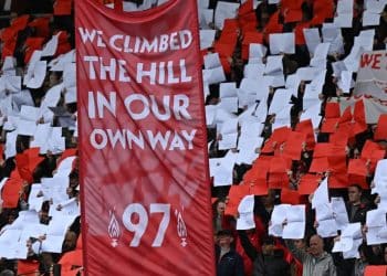 Hillsborough - people hold up red and white pieces of paper and a fabric banner with the words ' We climbed the hill in our own way - 97' to commemorate the 97 victims of the hillsborough disaster