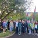 A large group of walkers stand together under a large tree waving Palestine flags Gaza