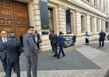 Activists outside the Science Museum as guests arrive for Adani reception, holidng a banner: The Science Museum: "complicit in human rights buses, fraud, bribery, climate destruction, genocide."