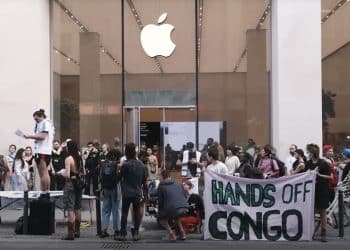 Group of protesters stand outside an Apple store with a banner that reads: "Hands off Congo" iPhone 17