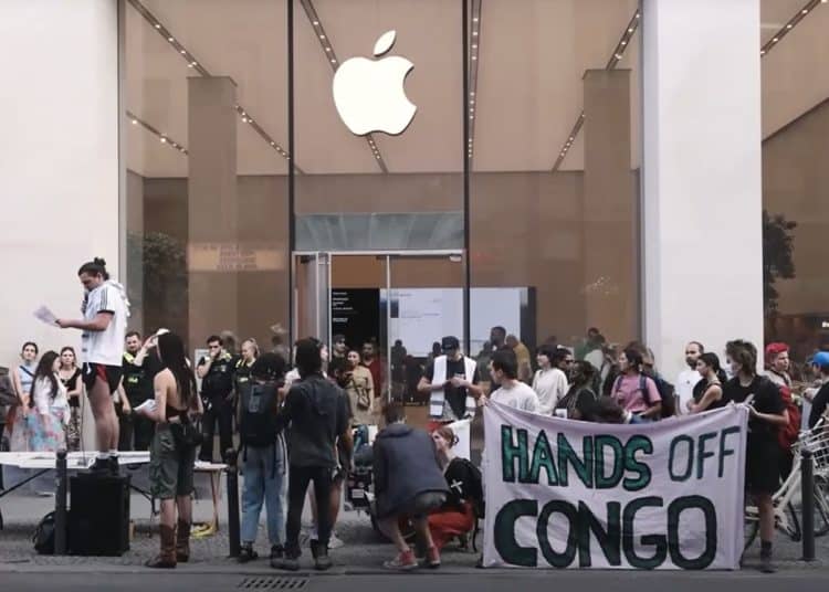 Group of protesters stand outside an Apple store with a banner that reads: "Hands off Congo" iPhone 17